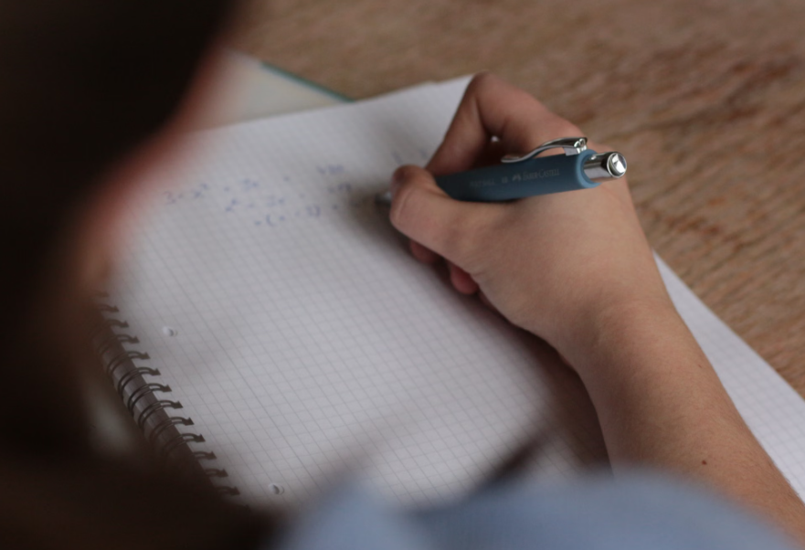 Close-up of a student writing notes by hand in a notebook